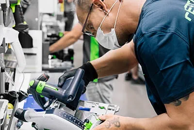 Les composants de la scie plongeante Festool TSC 55 K sont assemblés sur l'établi.
