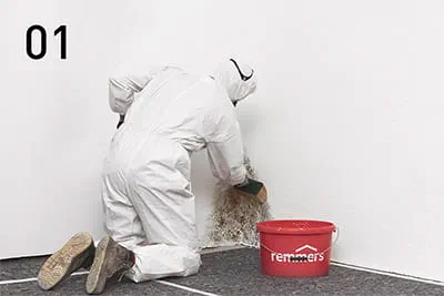 Commencer par examiner le support et recouvrir les sols ainsi que le mobilier, puis utiliser le produit Sporenbinder de Remmers pour enduire les surfaces attaquées par les moisissures.