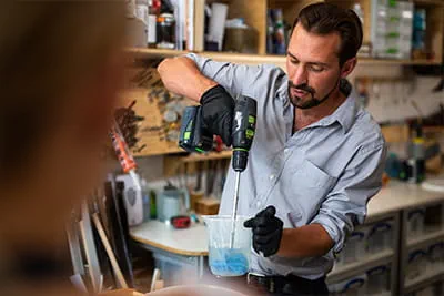 Richard utilise une perceuse-visseuse sans fil pour remuer la résine destinée à ses œuvres d'art