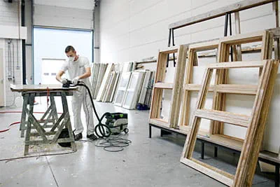 À l'occasion de projets de rénovation de grande envergure, des fenêtres et des portes sont remises en état avec soin dans les vastes ateliers.