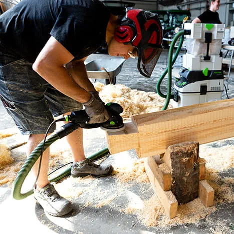 Une constructrice de saunas lors du ponçage d'une surface en bois avec la Rotex 150 de Festool.